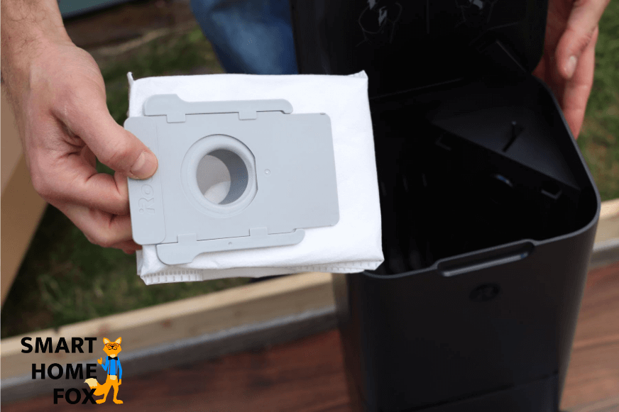 Inserting a disposable dust bag into the auto-empty dustbin.